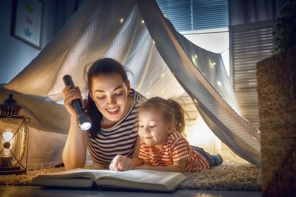 reading a book with a torch in an inside tent