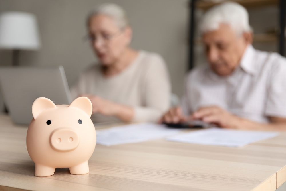 older couple in background with piggy bank in foreground