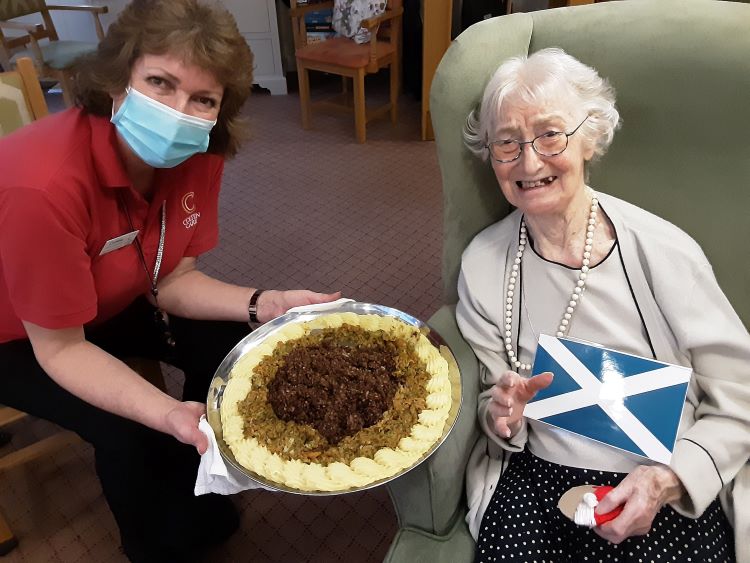 Amberwood House resident Wilma Millett receives a haggis delivery from Companionship Team member Corrine Wareham
