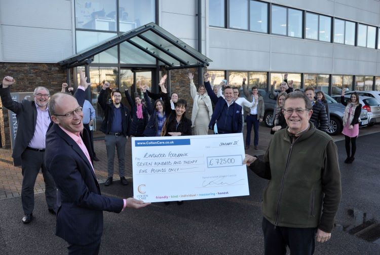 Watched by colleagues outside Colten House in Ringwood, Mark Aitchison, Chief Executive of Colten Care, presents a cheque for £725 to Chris Lee, standing right, Chair of Trustees of Ringwood Foodbank. 