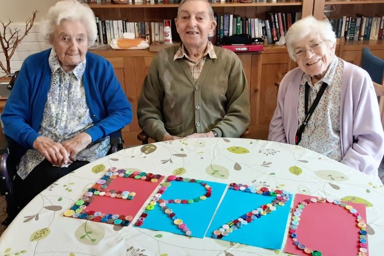 ON THE BUTTON. Kingfishers residents from left, Joyce Russell, Terry Vass and Patricia Cooke, spell out the ‘ER70’ message in a decoration made with buttons 