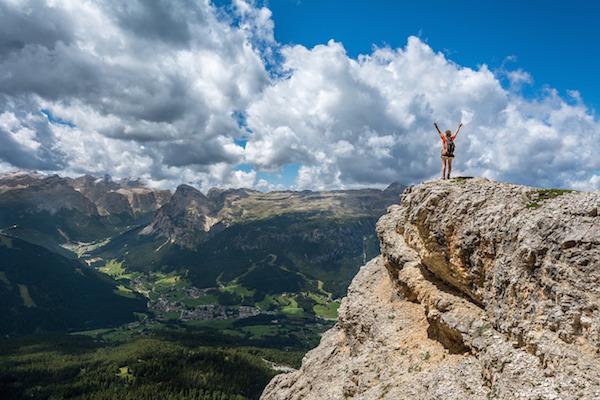 person at the top of a mountain with arms in the air